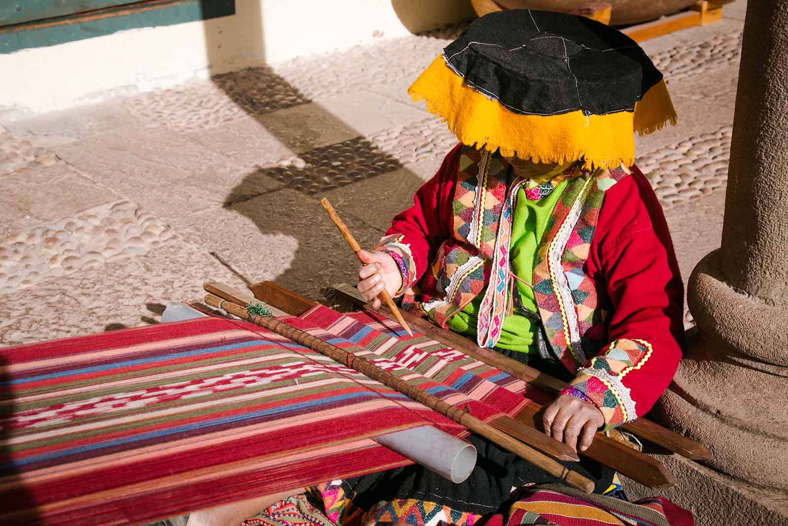 Seek out local artisans like this Quechua woman weaving with lama wool in a traditional way in Cusco, Per
