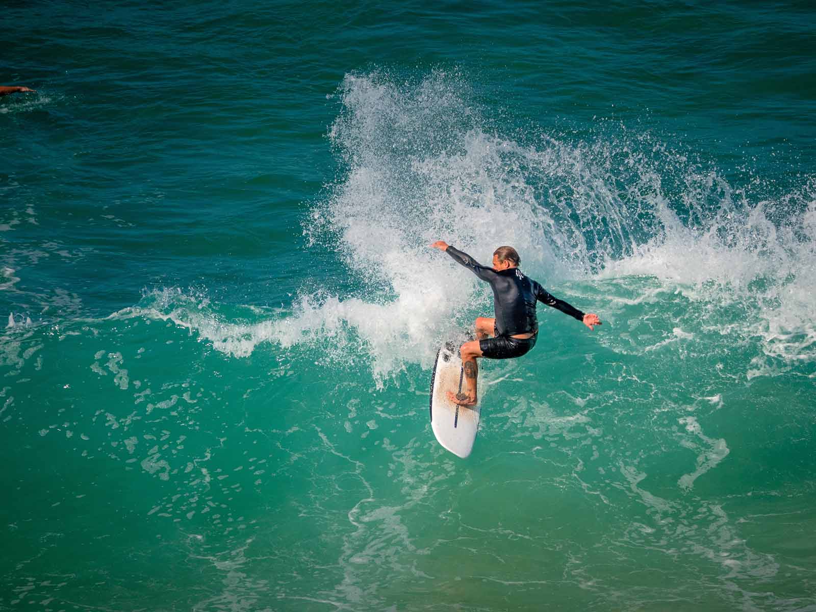 Surfer hitting the waves | How to travel from BNE Airport to the Gold Coast in a day