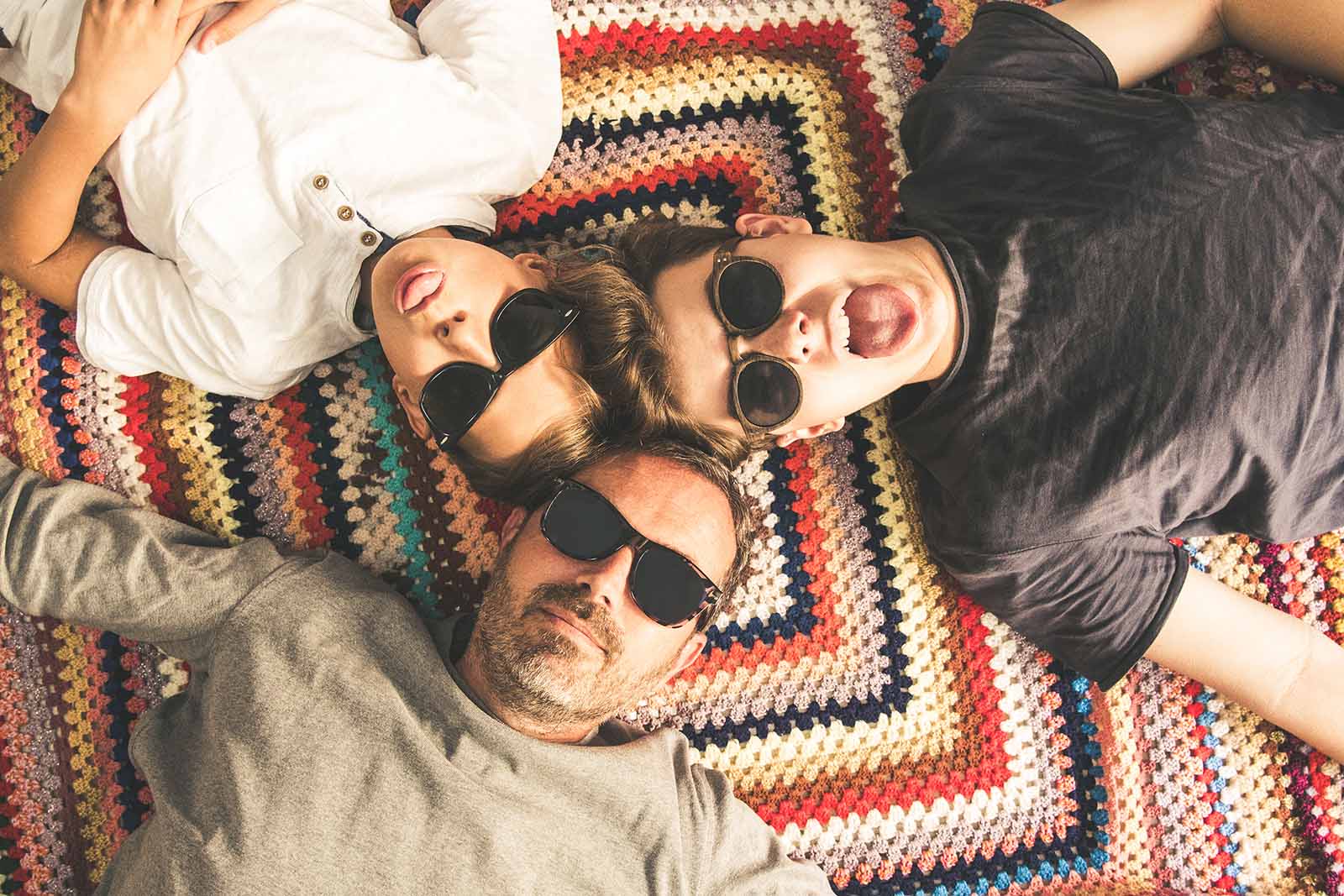 Dad and sons lying on a blanket relaxing | Top tips for travelling in a large group while keeping friendships intact