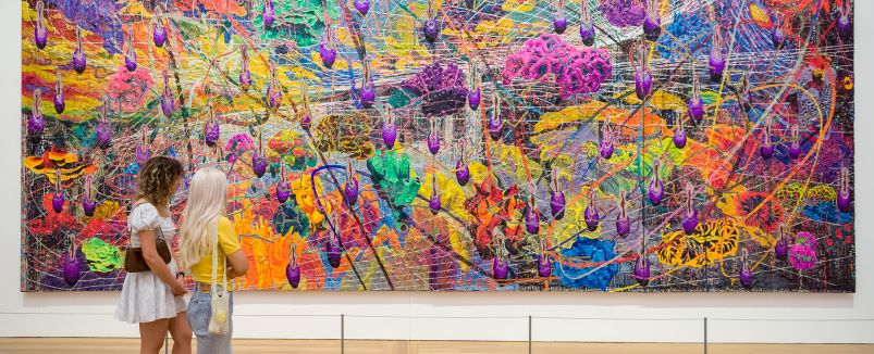 Two women looking at a large abstract painting by Thasnai Sethaseree Two women looking at a large abstract painting by Thasnai Sethaseree