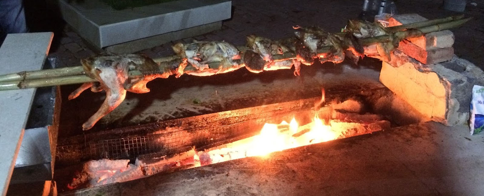 Chickens on a spit roasting over flaming charcoals 