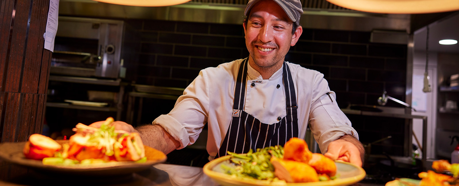 A smiling chef serving two plates of food
