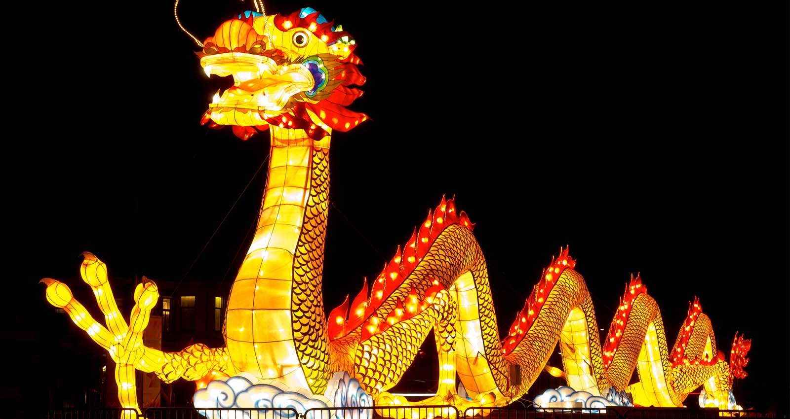 A large illuminated gold and red dragon on black background