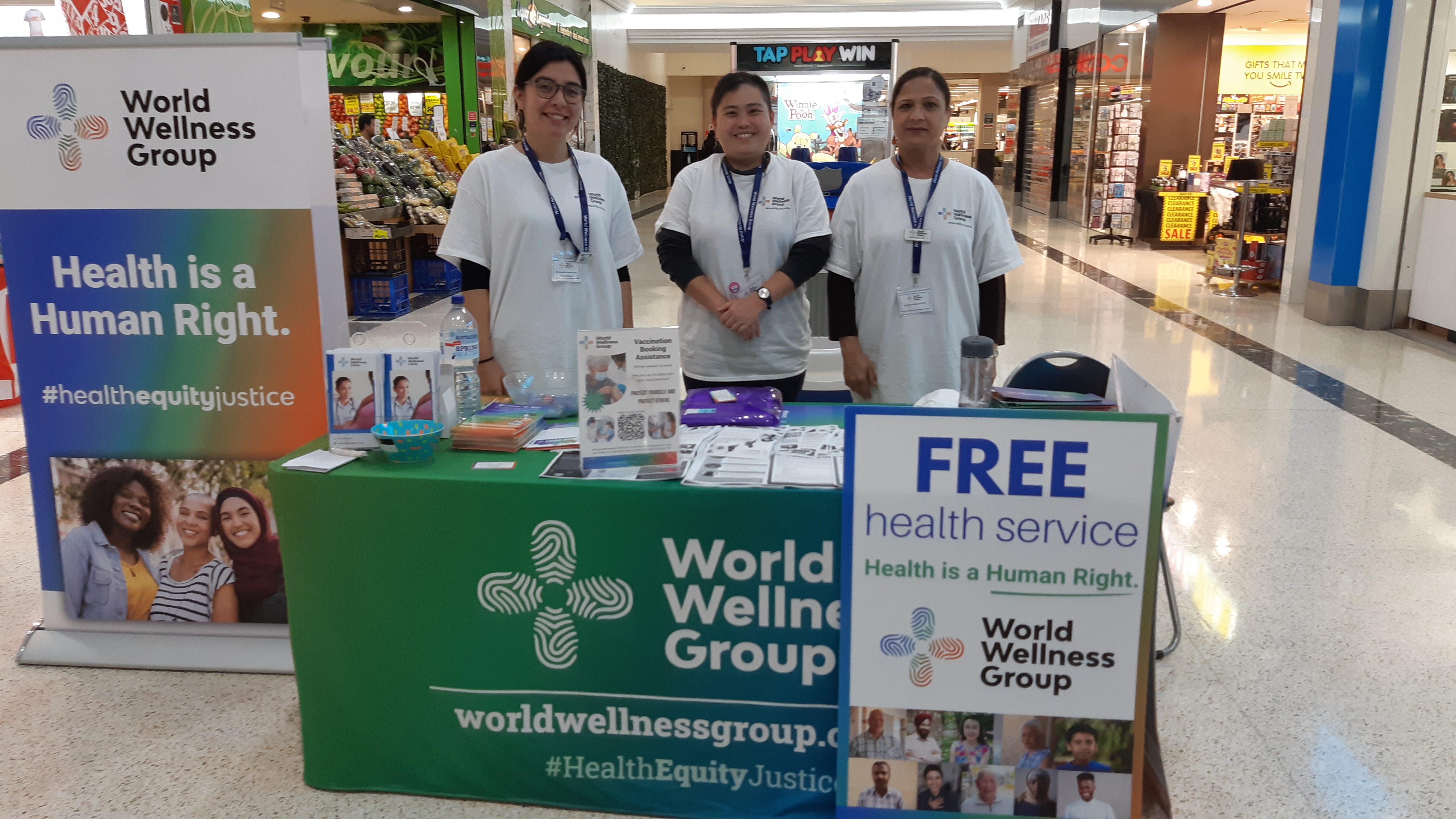 Three ladies from World Wellness Group at a pop up stall in a shopping centre