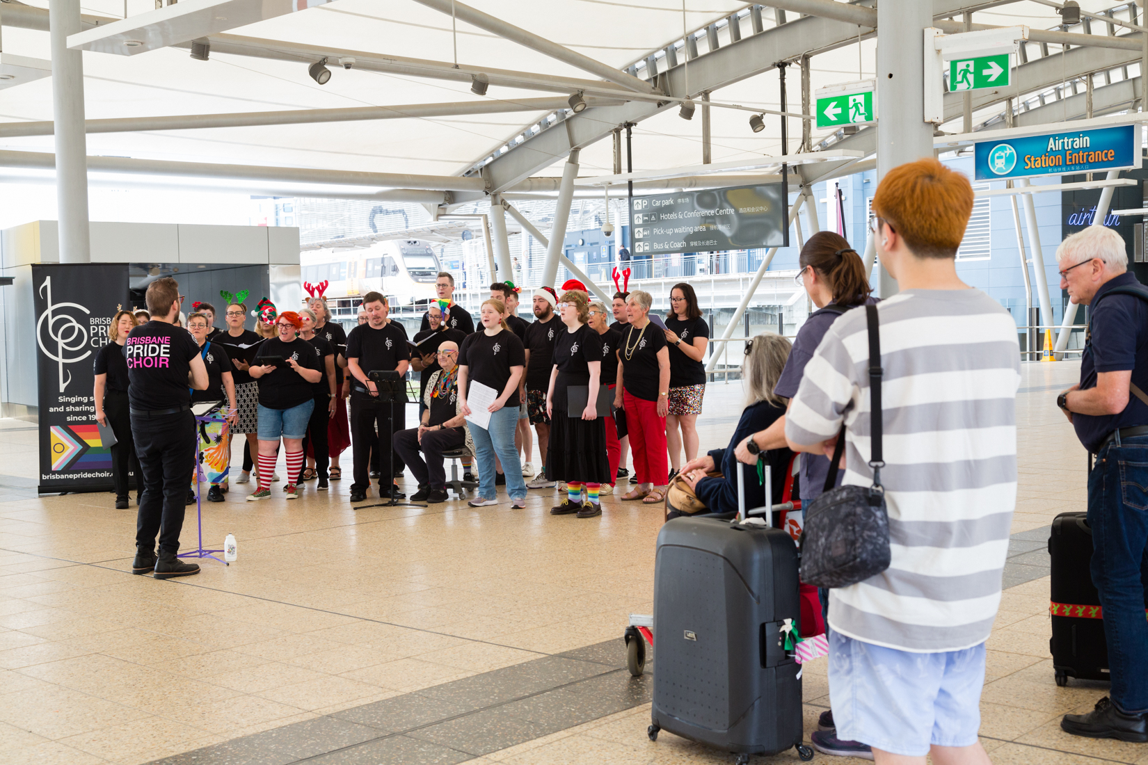 Brisbane Pride Choir performing at the airport with passengers watching them