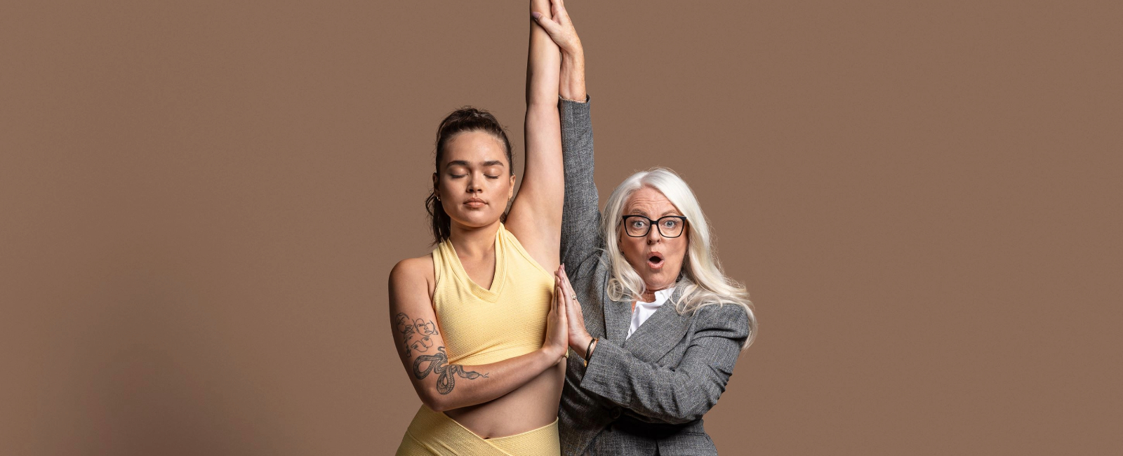 A person in workout attire and a person in a suit doing a yoga pose