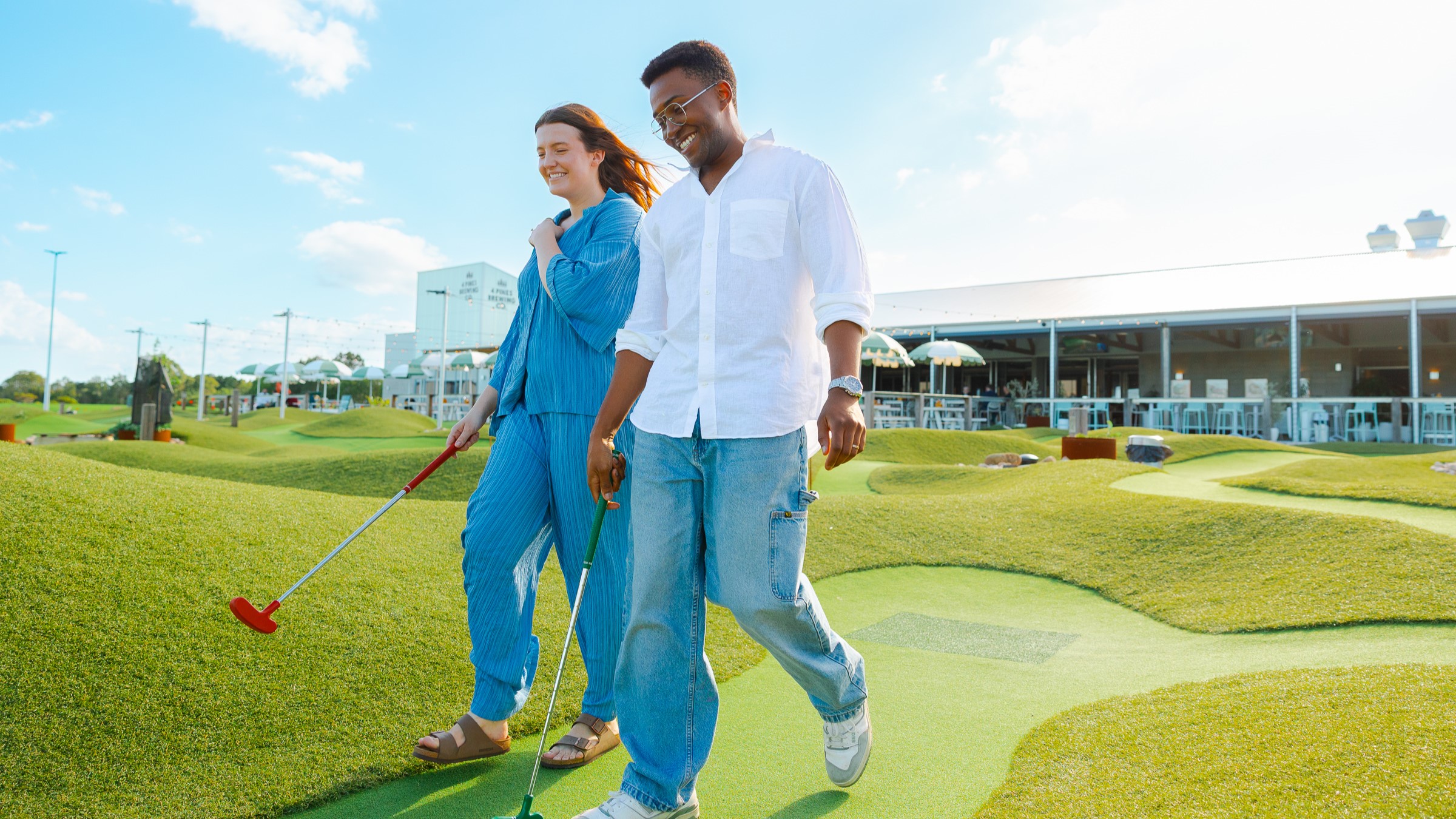 Two people walking across a golf course