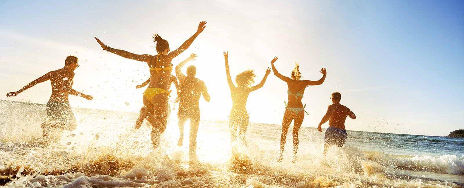 Group of friends running into the ocean | Top tips for travelling in a large group while keeping friendships intact