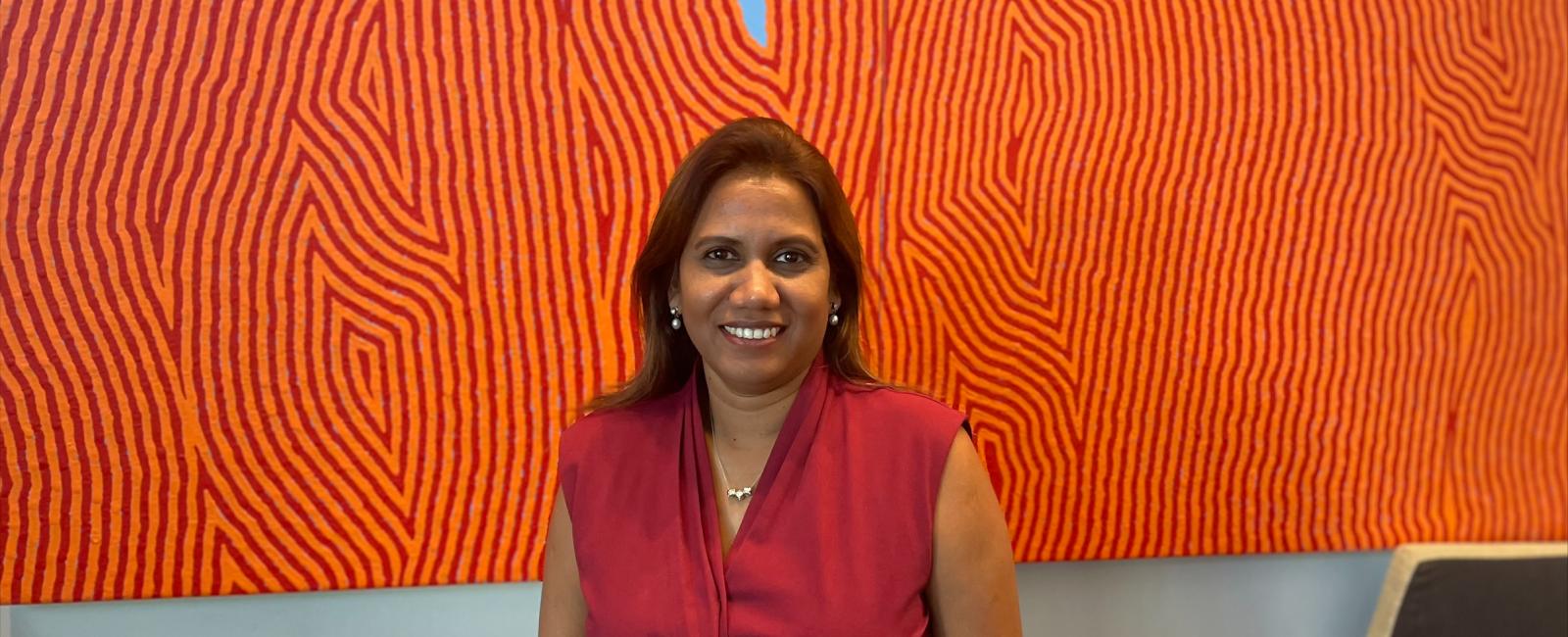 Shushan standing in front of orange artwork