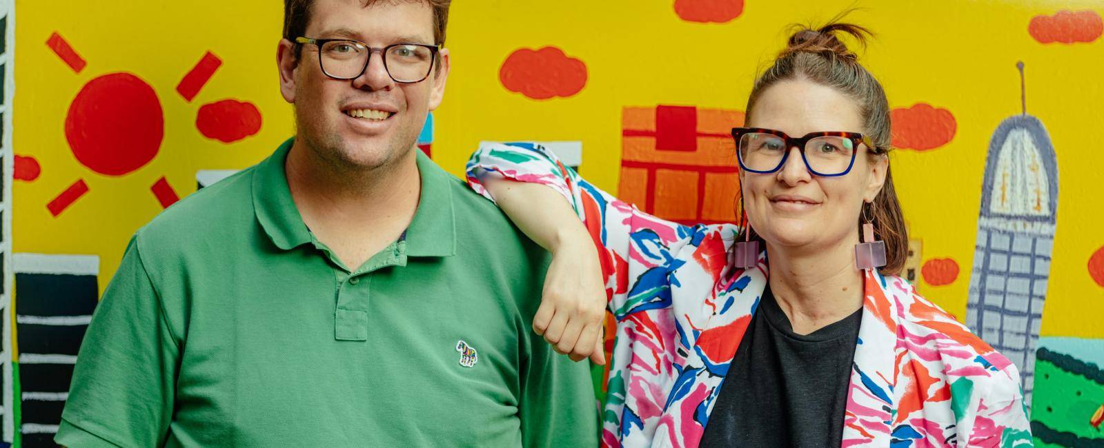 A man in a green shirt standing with a lady in a colourful jacket and black shirt