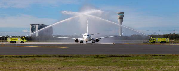 First plane on the new Brisbane Runway with fire trucks shooting water cannons to welcome it