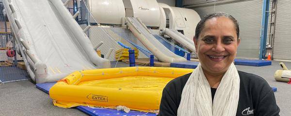 Harsha Patel standing in front of aviation training equipment - rafts and evacuation slides.  