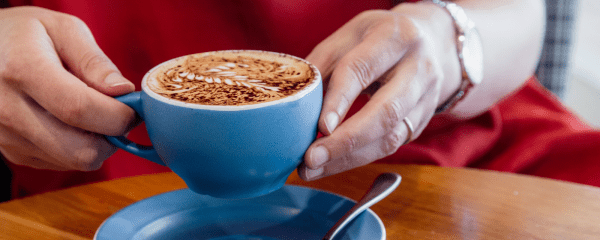 Person holding coffee at Coretto Cafe & Bar