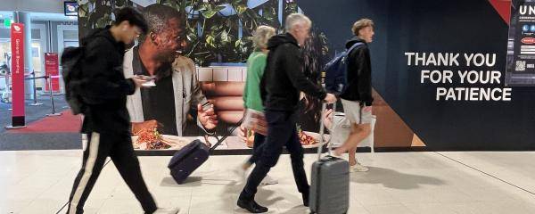 People walking past hoarding at the Domestic Terminal