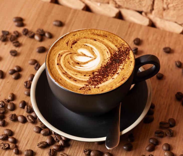 a cup of coffee with coffee beans around it