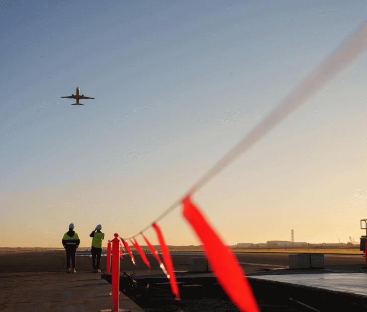 Plane flying over workers on the Legacy Runway Plane flying over workers on the Legacy Runway