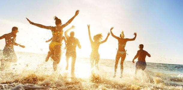 Group of friends running into the ocean | Top tips for travelling in a large group while keeping friendships intact