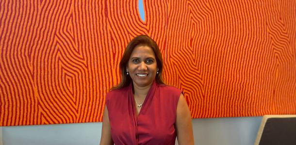 Shushan standing in front of orange artwork