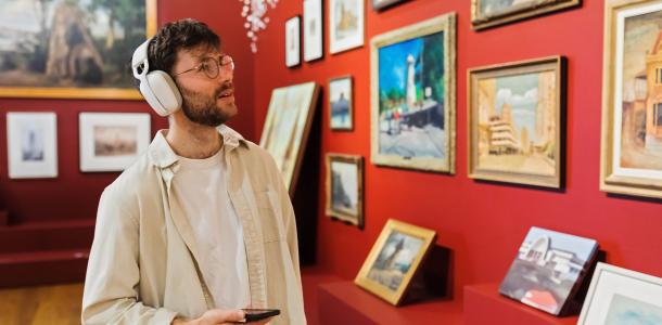 A man wearing headphones looking at artwork