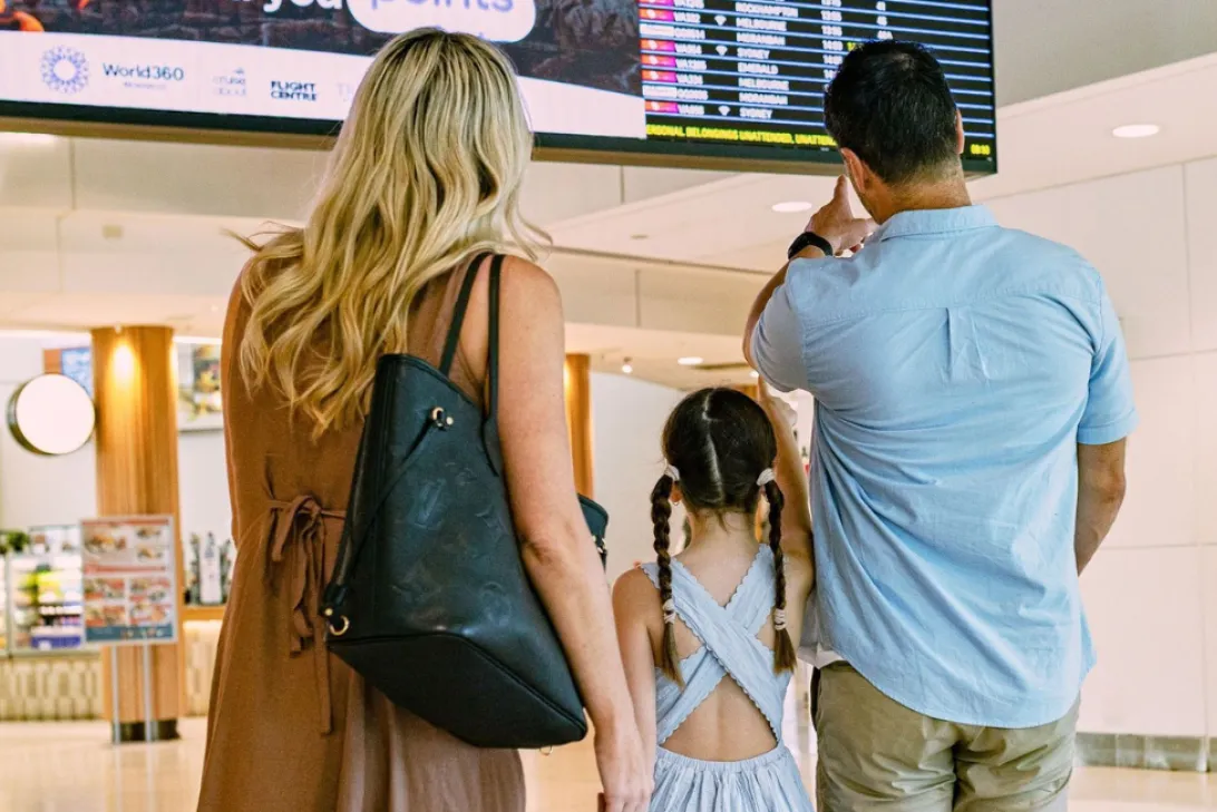 Two adults and a child looking at flight information