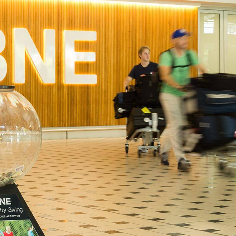 Passenger donating money to a Charity Giving Globe at the International Terminal