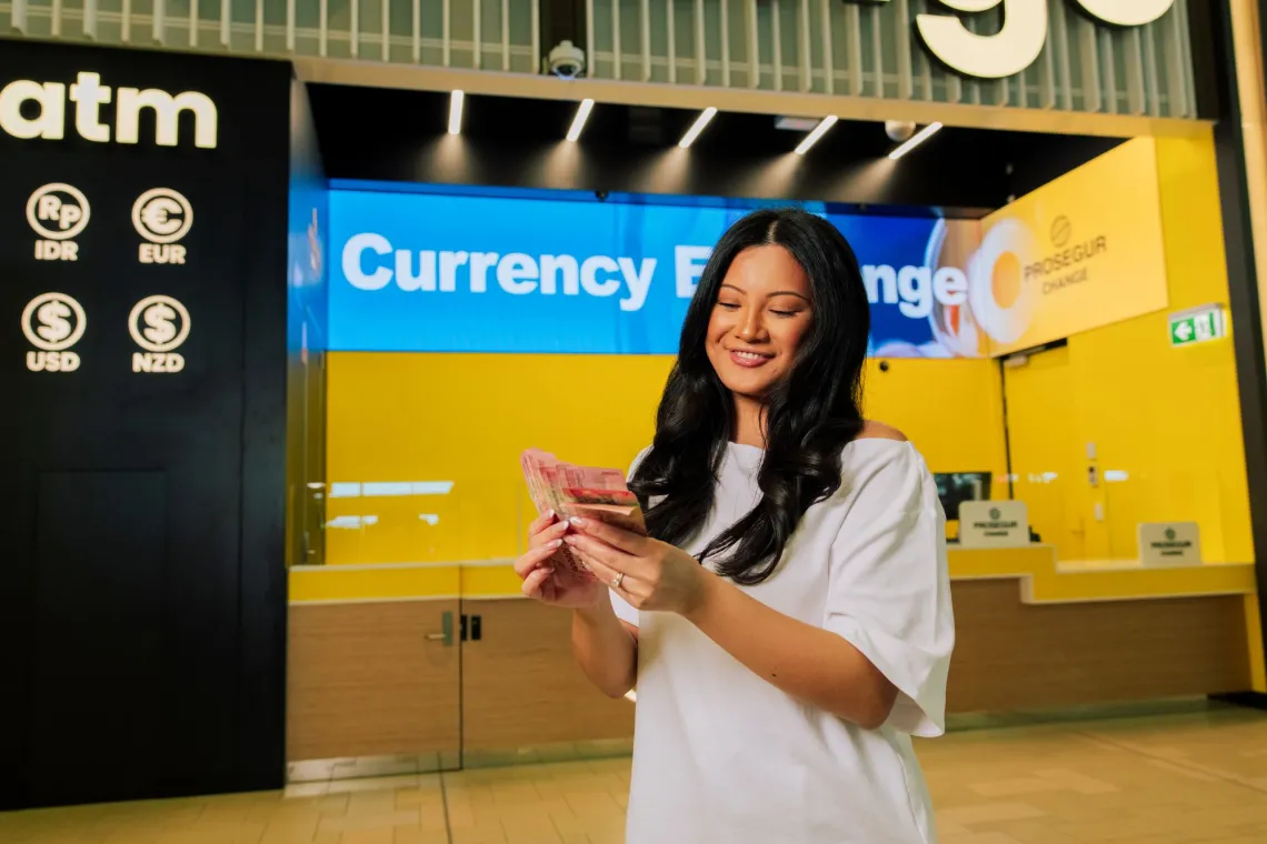 Woman standing infront of the prosegur exchange storefront counting her currency